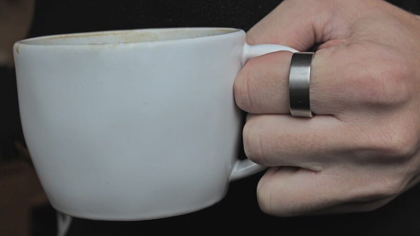 ultrahuman ring air on hand holding a coffee cup